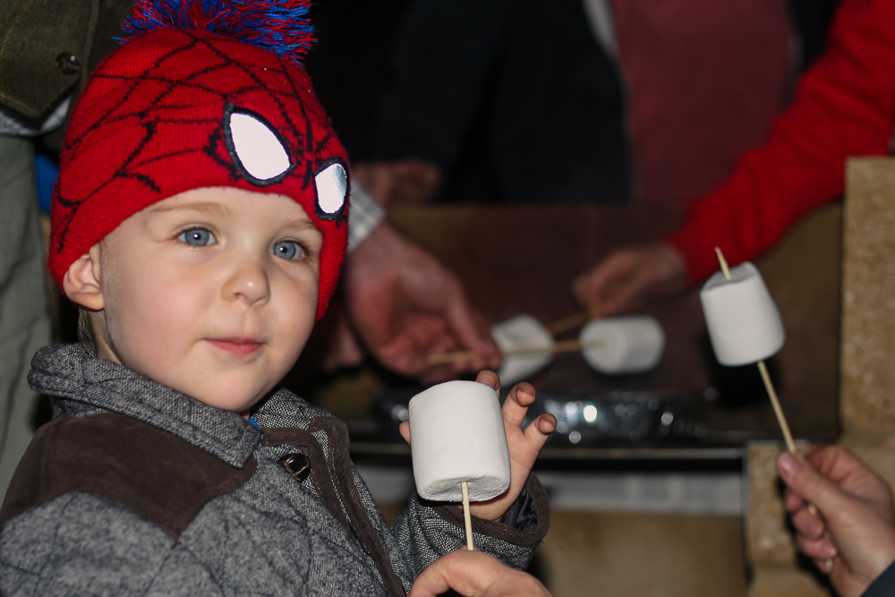 Pickle enjoying toasting marshmallows outside at Center Parcs in a Spiderman hat