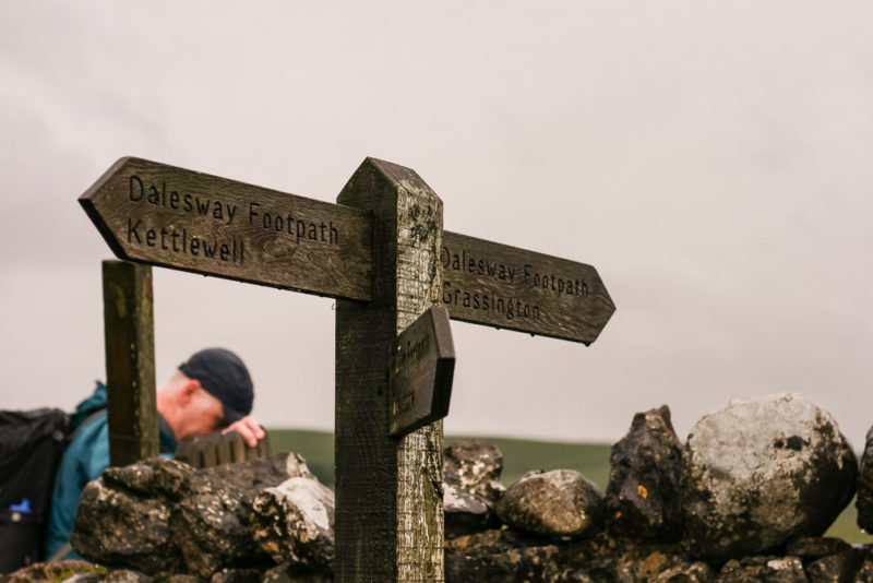 Signpost by a dry stone wall during a walk with Blacks and The North Face by Team Walking