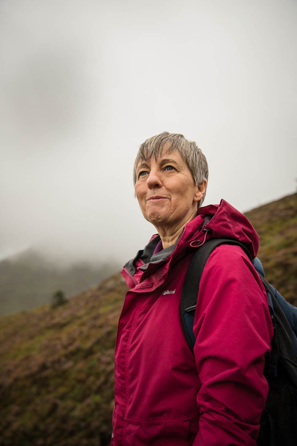 Lady looking out with awe with mist behind wearing waterproofs on a Welsh mountain walk
