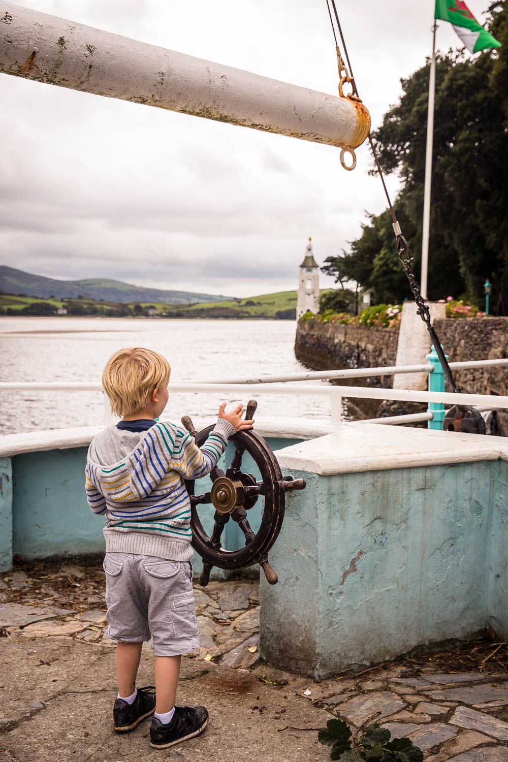 Blonde child with back to camera attempting to steer a boat at Portmeirion