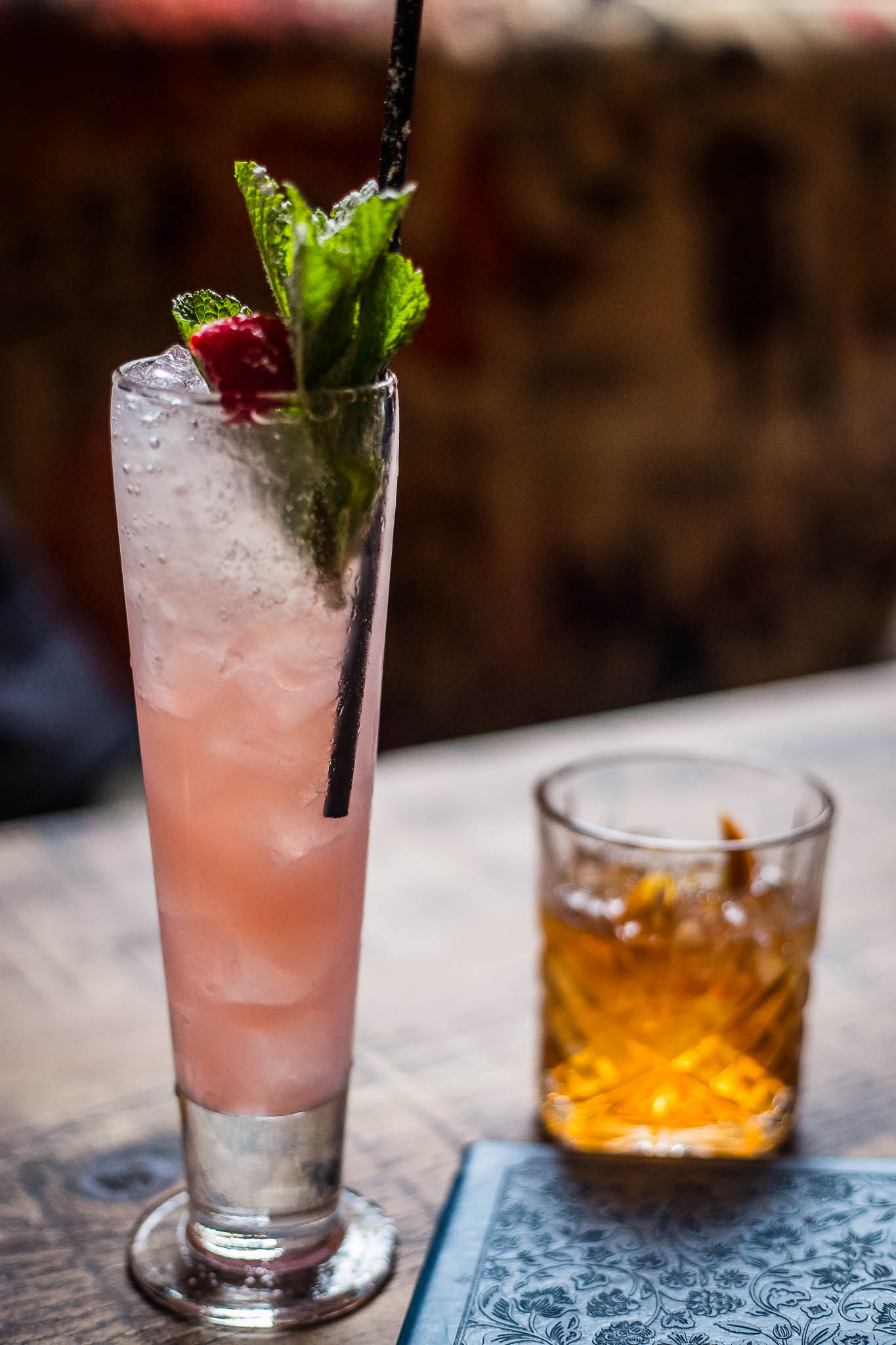 The Raspberry and Rhubarb Sling cocktail with an Old Fashioned cocktail in the background
