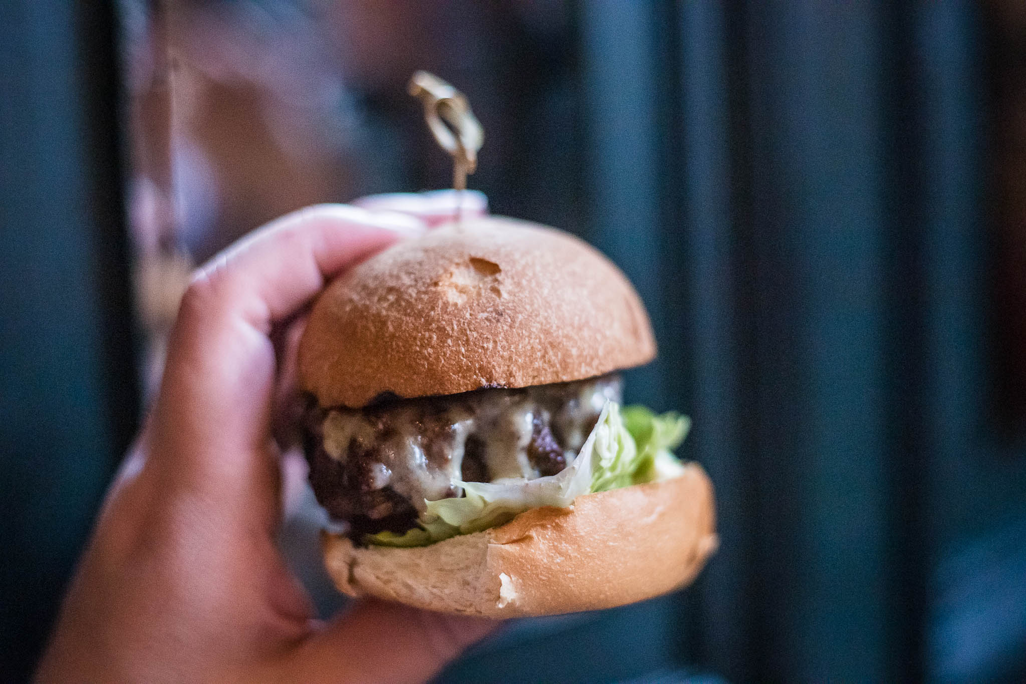A mini burger being held with one hand.
