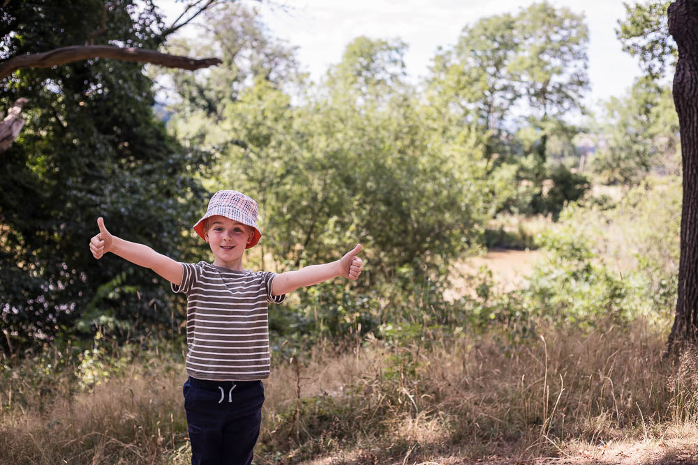 Child giving the thumbs up to the camera at the start of a woodland walk in Worcestershire